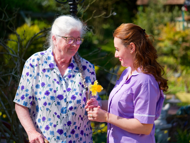 Elder person in garden with carer